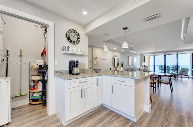 200 Ocean Trail Way Unit 701, Jupiter, FL 33477 - kitchen with open floor plan, light wood-style floors, a peninsula, white cabinetry, and light stone counters