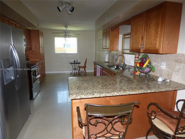 5501 Johnson St, Hollywood, FL 33021 - kitchen with appliances with stainless steel finishes, ceiling fan, brown cabinetry, light stone counters, and decorative backsplash