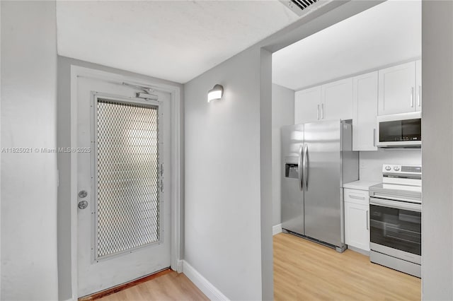 9311 Orange Grove Dr Unit 409, Davie, FL 33324 - kitchen with stainless steel appliances, light wood-style floors, white cabinets, and light countertops