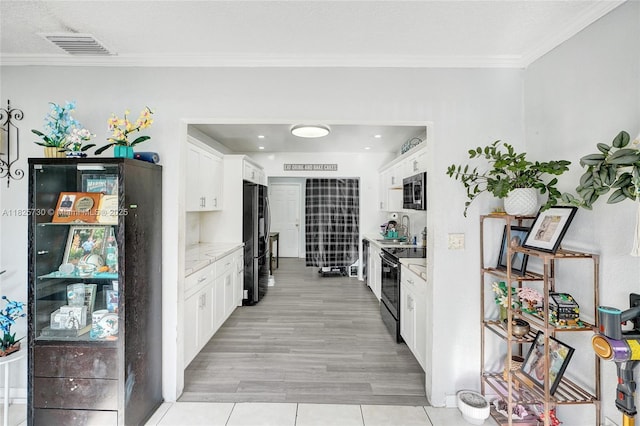 17415 NW 27th Ct, Miami Gardens, FL 33056 - kitchen featuring black appliances, white cabinets, crown molding, light tile patterned floors, and light stone countertops