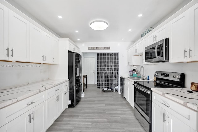17415 NW 27th Ct, Miami Gardens, FL 33056 - kitchen with stainless steel appliances, white cabinets, light wood finished floors, recessed lighting, and light stone countertops