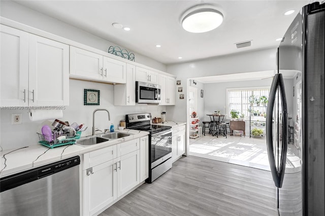 17415 NW 27th Ct, Miami Gardens, FL 33056 - kitchen with appliances with stainless steel finishes, white cabinets, recessed lighting, light wood-style floors, and light stone countertops