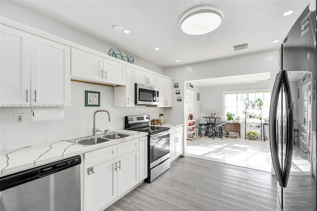 17415 NW 27th Ct, Miami Gardens, FL 33056 - kitchen with stainless steel appliances, white cabinetry, light stone counters, light wood finished floors, and recessed lighting