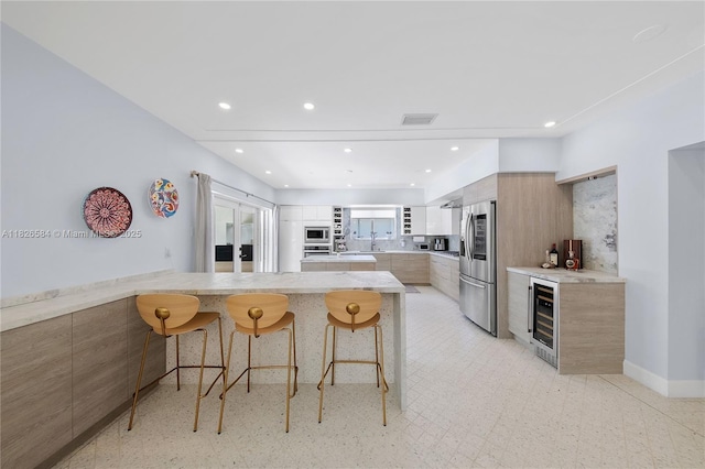2010 NE 122nd Rd, North Miami, FL 33181 - kitchen featuring appliances with stainless steel finishes, modern cabinets, beverage cooler, a kitchen breakfast bar, and a peninsula