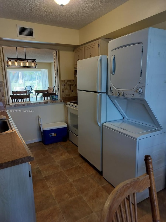 13791 Flora Pl Unit B, Delray Beach, FL 33484 - kitchen featuring white appliances, stacked washer / drying machine, a textured ceiling, backsplash, and dark countertops