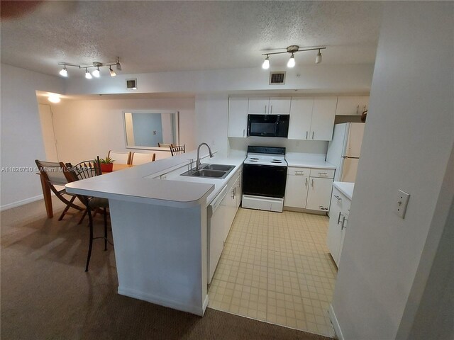 2640 S University Dr Unit 125, Davie, FL 33328 - kitchen with white appliances, a peninsula, a textured ceiling, light countertops, and a kitchen breakfast bar