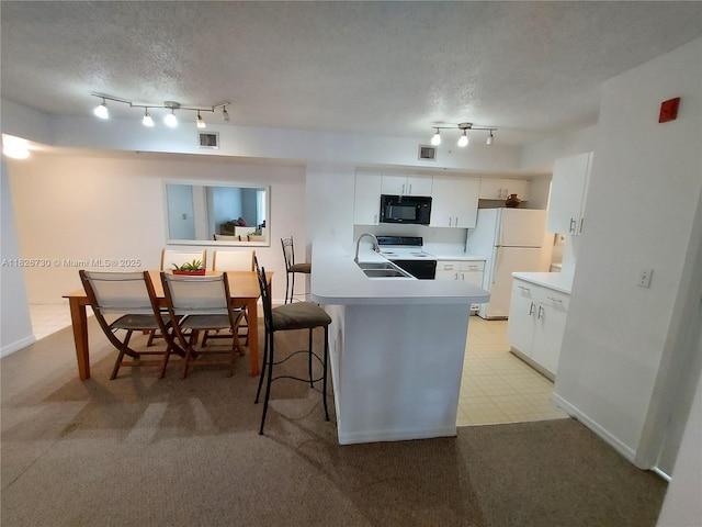 2640 S University Dr Unit 125, Davie, FL 33328 - kitchen with black microwave, freestanding refrigerator, track lighting, electric range, and a peninsula