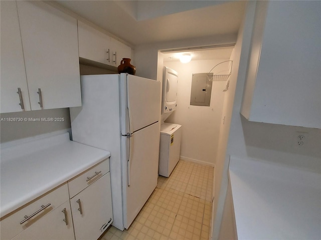 2640 S University Dr Unit 125, Davie, FL 33328 - kitchen with stacked washer / drying machine, electric panel, freestanding refrigerator, light countertops, and white cabinets