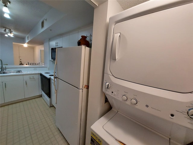 2640 S University Dr Unit 125, Davie, FL 33328 - kitchen with white appliances, stacked washer / drying machine, light flooring, light countertops, and white cabinets