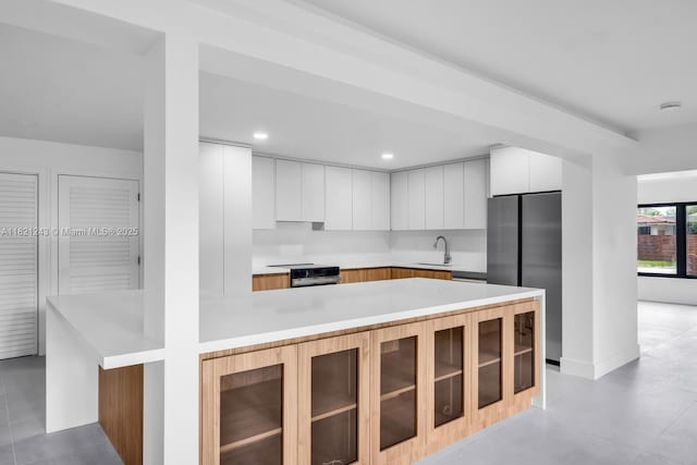 220 NE 105th St, Miami Shores, FL 33138 - kitchen featuring freestanding refrigerator, modern cabinets, stove, a peninsula, and white cabinetry