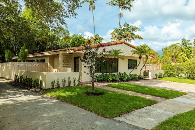 220 NE 105th St, Miami Shores, FL 33138 - mediterranean / spanish home featuring a fenced front yard, a tile roof, and stucco siding