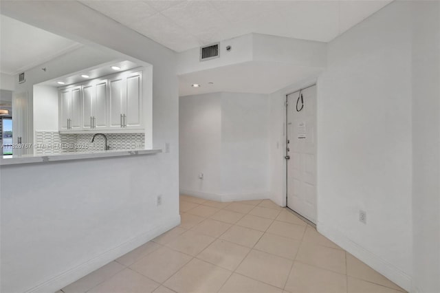 13800 SW 5th Ct Unit 101M, Pembroke Pines, FL 33027 - kitchen featuring light countertops, backsplash, white cabinets, and light tile patterned floors