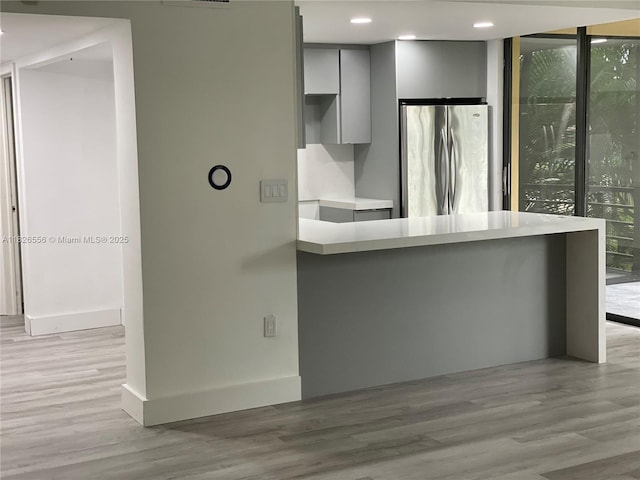 671 NE 195th St Unit 228E, Miami, FL 33179 - kitchen featuring freestanding refrigerator, gray cabinets, modern cabinets, light wood-style flooring, and light countertops