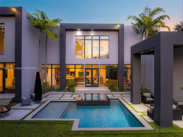 1009 NE 104th St, Miami Shores, FL 33138 - back of house at dusk with stucco siding and a patio area