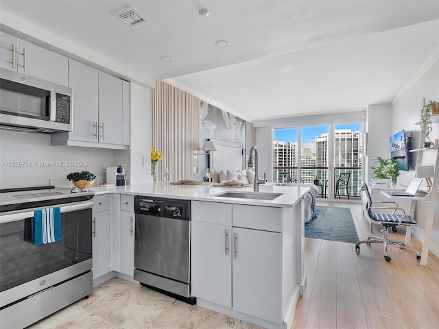2889 Mcfarlane Rd Unit 1908, Miami, FL 33133 - kitchen with stainless steel appliances, a peninsula, ornamental molding, light countertops, and open floor plan