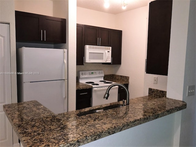 6001 SW 70th St Unit 324, South Miami, FL 33143 - kitchen with white appliances, dark stone countertops, dark brown cabinets, and a peninsula