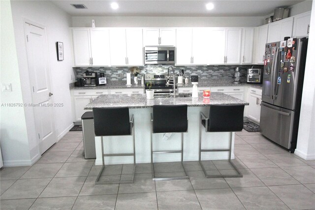 2574 SW Cameo Blvd, Port St Lucie, FL 34953 - kitchen featuring stainless steel appliances, backsplash, an island with sink, white cabinets, and recessed lighting