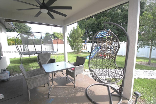 2574 SW Cameo Blvd, Port St Lucie, FL 34953 - fenced backyard featuring a trampoline, a playground, a ceiling fan, outdoor dining space, and a patio area