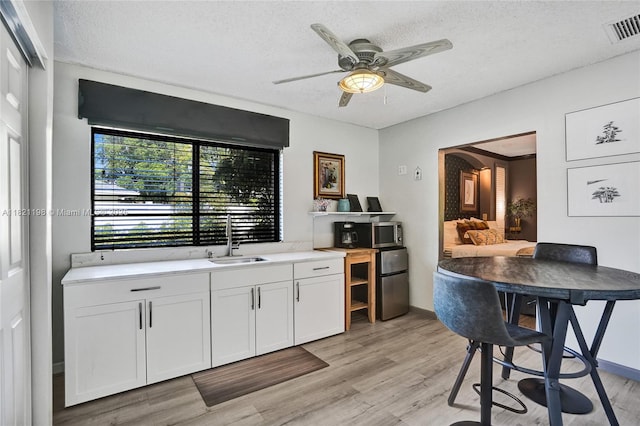 10030 SW 8th St, Pembroke Pines, FL 33025 - kitchen featuring light wood-style floors, a ceiling fan, a textured ceiling, white cabinetry, and light countertops