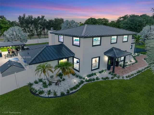 12220 Tara Dr, Plantation, FL 33325 - back of property at dusk with a standing seam roof, a metal roof, stucco siding, and a chimney
