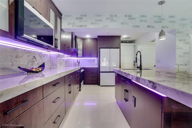 12220 Tara Dr, Plantation, FL 33325 - kitchen featuring freestanding refrigerator, light stone counters, pendant lighting, light tile patterned floors, and glass insert cabinets
