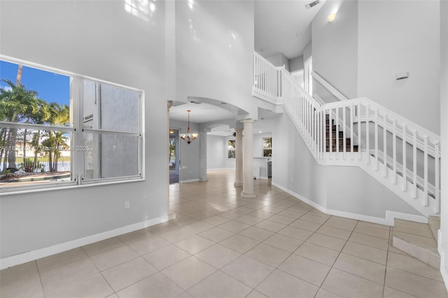 6425 SW 164th Ave, Miami, FL 33193 - unfurnished living room with ornate columns, a high ceiling, tile patterned floors, a chandelier, and arched walkways