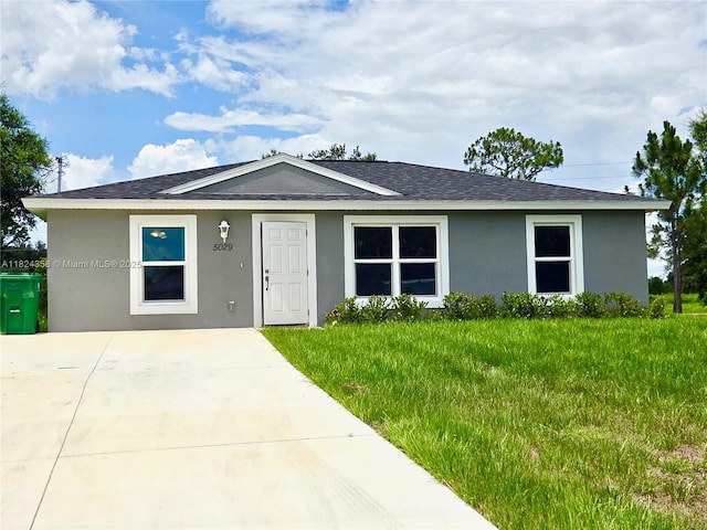 5029 N Dogwood Cir, La Belle, FL 33935 - view of front facade with roof with shingles, stucco siding, and a front lawn