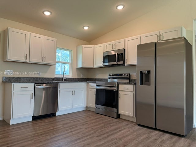 5029 N Dogwood Cir, La Belle, FL 33935 - kitchen with appliances with stainless steel finishes, white cabinetry, vaulted ceiling, wood finished floors, and recessed lighting