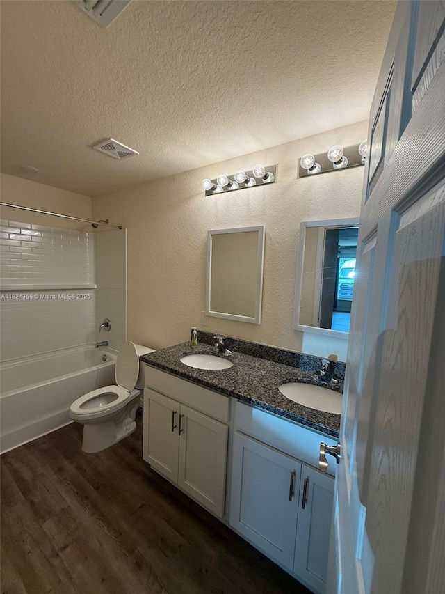 5029 N Dogwood Cir, La Belle, FL 33935 - bathroom featuring a textured ceiling, double vanity, wood finished floors, tub / shower combination, and a textured wall