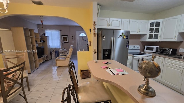 3640 SW 13th St, Miami, FL 33145 - kitchen featuring white appliances, arched walkways, glass insert cabinets, and white cabinetry