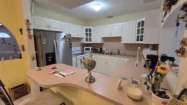 3640 SW 13th St, Miami, FL 33145 - kitchen featuring white appliances, a breakfast bar area, glass insert cabinets, a peninsula, and a textured ceiling
