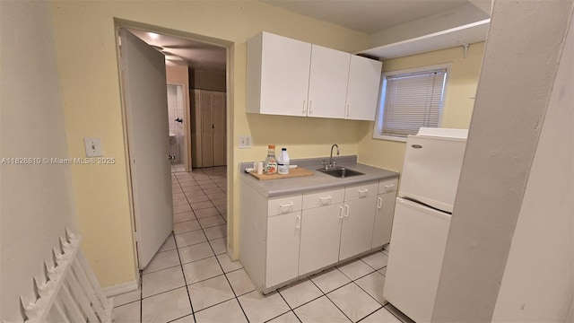 3640 SW 13th St, Miami, FL 33145 - kitchen with freestanding refrigerator, white cabinetry, light tile patterned floors, and light countertops