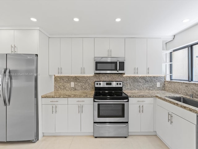 8075 SW 86th Ter, Miami, FL 33143 - kitchen with appliances with stainless steel finishes, white cabinets, decorative backsplash, light stone countertops, and recessed lighting
