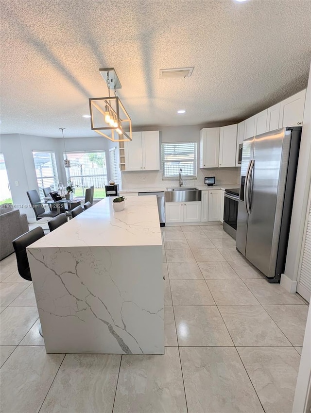 335 SW 183rd Way, Pembroke Pines, FL 33029 - kitchen with stainless steel appliances, white cabinetry, a textured ceiling, light stone counters, and pendant lighting