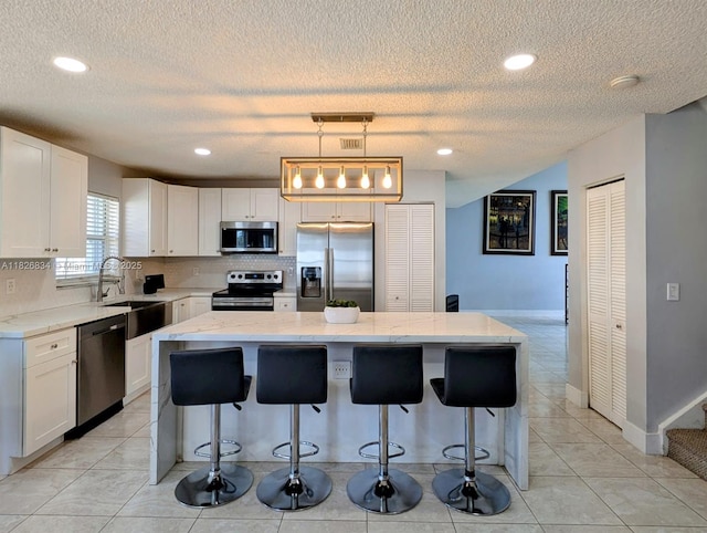335 SW 183rd Way, Pembroke Pines, FL 33029 - kitchen with stainless steel appliances, white cabinets, a kitchen island, a textured ceiling, and light stone countertops