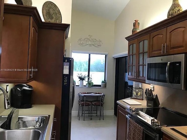 15405 N Miami Lakeway N Unit 307, Miami Lakes, FL 33014 - kitchen featuring stainless steel appliances, glass insert cabinets, an office area, high vaulted ceiling, and dark brown cabinetry
