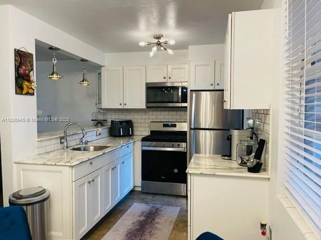1698 Jefferson Ave Unit 9, Miami Beach, FL 33139 - kitchen featuring appliances with stainless steel finishes, decorative backsplash, white cabinets, and light stone countertops