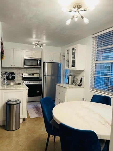 1698 Jefferson Ave Unit 9, Miami Beach, FL 33139 - kitchen with stainless steel appliances, tasteful backsplash, white cabinets, finished concrete floors, and glass insert cabinets