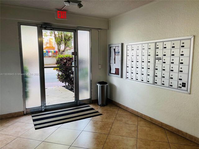 1698 Jefferson Ave Unit 9, Miami Beach, FL 33139 - doorway with mail area, a textured wall, crown molding, a textured ceiling, and tile patterned floors
