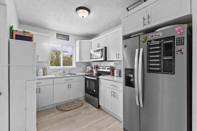 7307 SW 8th St, North Lauderdale, FL 33068 - kitchen featuring stainless steel appliances, light countertops, white cabinetry, light wood finished floors, and a textured ceiling