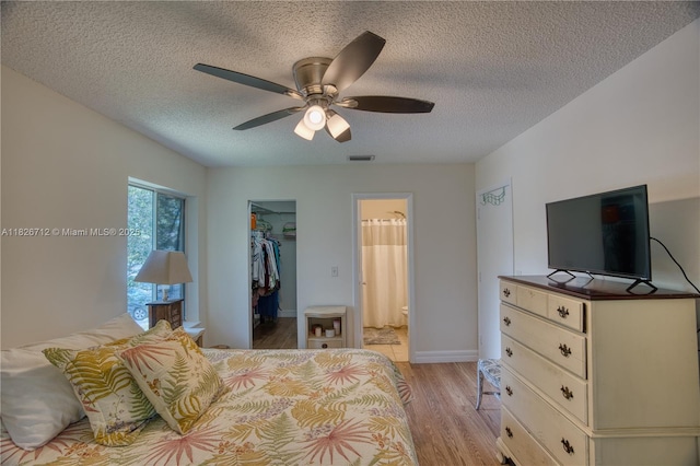 6286 Chasewood Dr Unit G, Jupiter, FL 33458 - bedroom with light wood-style flooring, a walk in closet, a textured ceiling, a ceiling fan, and ensuite bathroom