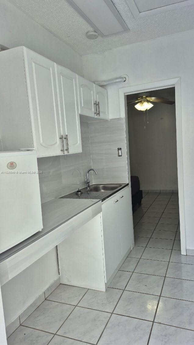 7322 SW 134th Pl, Miami, FL 33183 - kitchen with white cabinetry, light tile patterned floors, backsplash, and ceiling fan