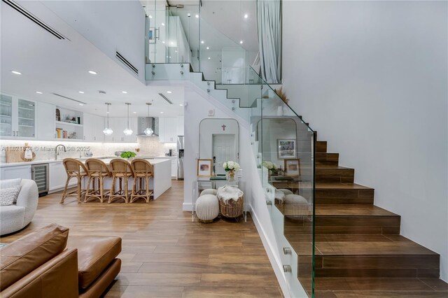 888 S Douglas Rd Unit 115, Coral Gables, FL 33134 - staircase with beverage cooler, wood finished floors, a high ceiling, and recessed lighting