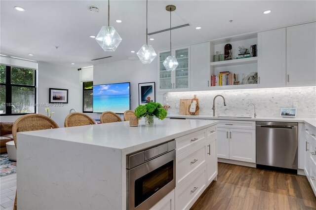 888 S Douglas Rd Unit 115, Coral Gables, FL 33134 - kitchen featuring appliances with stainless steel finishes, tasteful backsplash, a center island, white cabinetry, and recessed lighting