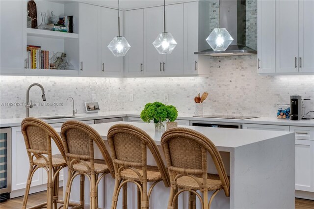 888 S Douglas Rd Unit 115, Coral Gables, FL 33134 - kitchen featuring wall chimney exhaust hood, light countertops, a breakfast bar area, pendant lighting, and white cabinetry