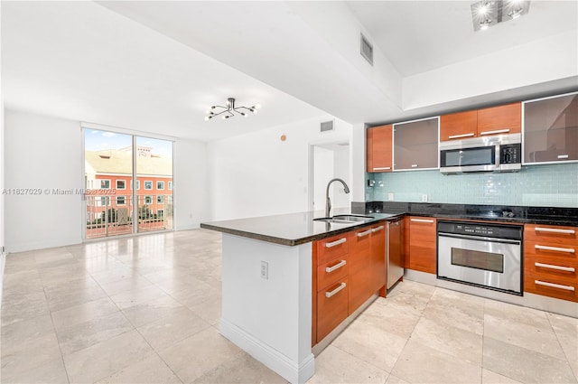 2030 S Douglas Rd Unit 807, Coral Gables, FL 33134 - kitchen featuring stainless steel appliances, decorative backsplash, a peninsula, dark stone countertops, and brown cabinets