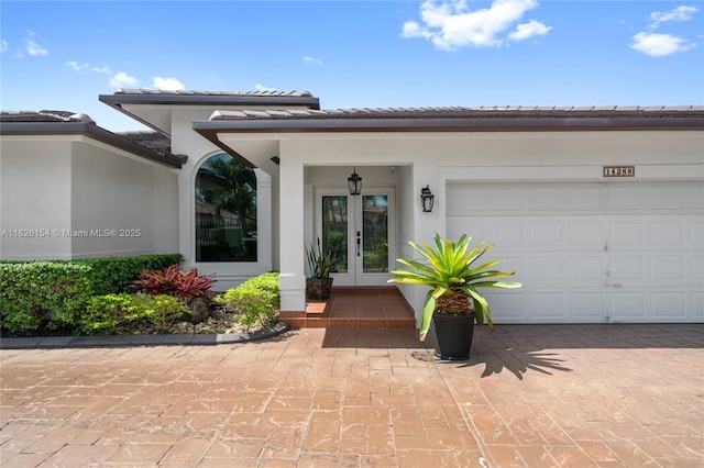 14288 SW 21st Ter, Miami, FL 33175 - property entrance featuring french doors, a tiled roof, stucco siding, an attached garage, and driveway