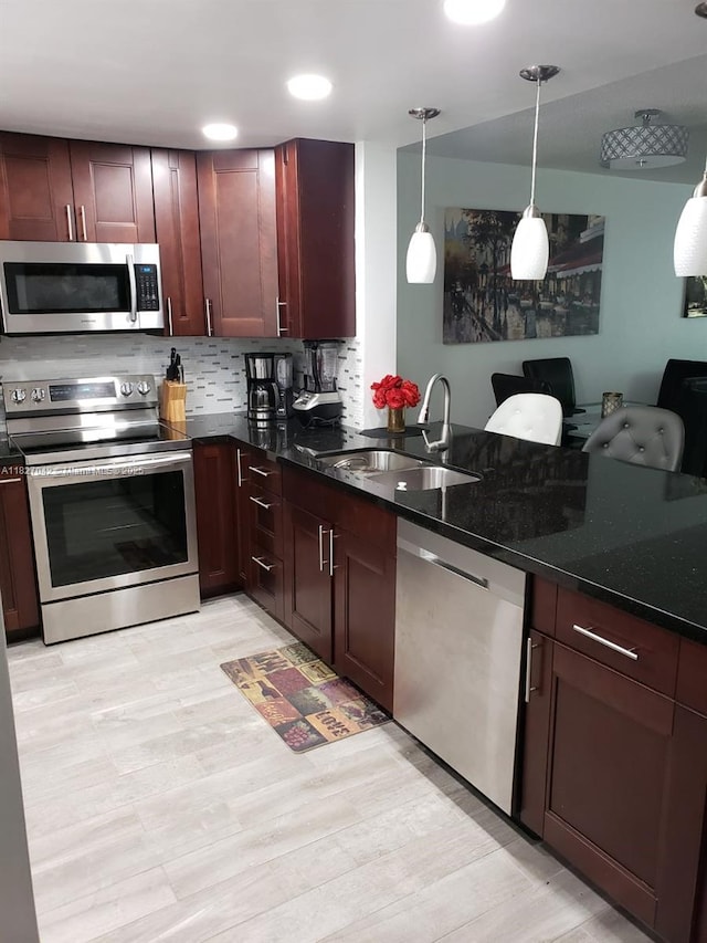 900 NE 12th Ave Unit 302, Hallandale Beach, FL 33009 - kitchen with appliances with stainless steel finishes, decorative backsplash, decorative light fixtures, dark stone counters, and light wood finished floors