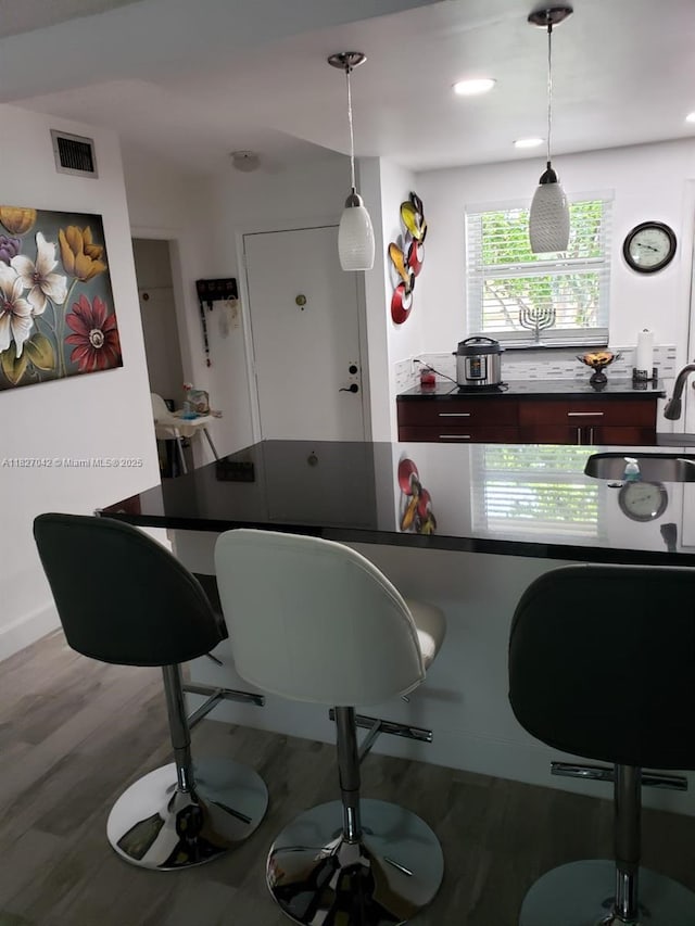 900 NE 12th Ave Unit 302, Hallandale Beach, FL 33009 - kitchen featuring dark countertops, a breakfast bar, wood finished floors, and decorative light fixtures
