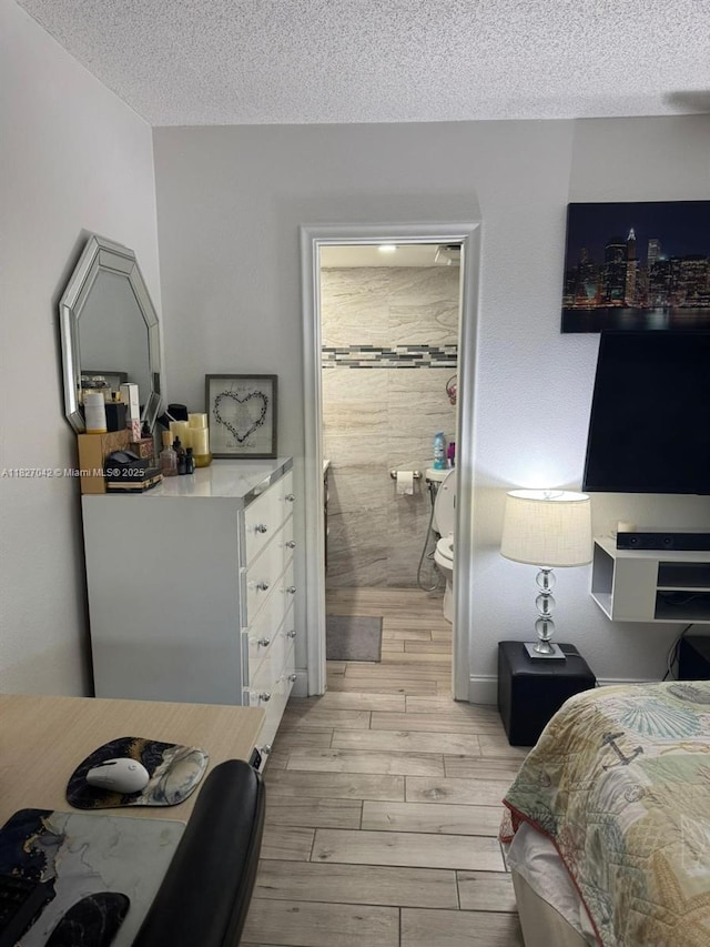 900 NE 12th Ave Unit 302, Hallandale Beach, FL 33009 - bedroom with light wood-style flooring, a textured ceiling, and ensuite bathroom